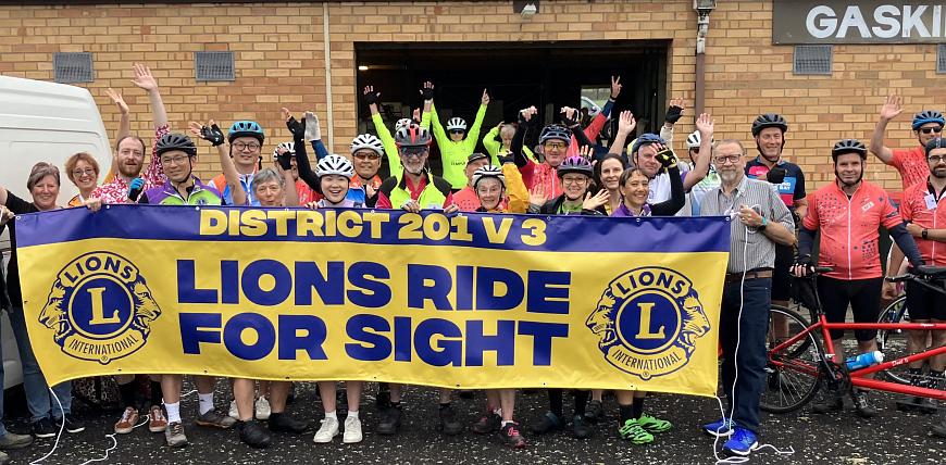 Participants on the ride (with bikes) behind a Lions banner